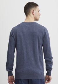 Pulover bărbătesc de culoare albastru închis, confecționat din material tricotat moale, având mâneci lungi, guler rotund și manșete și tiv ondulate.