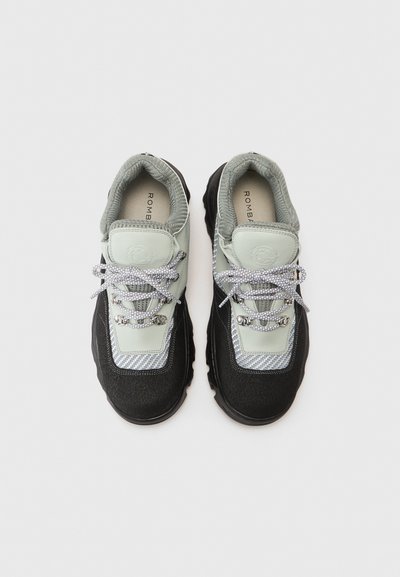 Sportliche Schuhe mit einem mintgrünen und schwarzen Design. Texturiertes Obermaterial mit reflektierenden Akzenten und runden Ösen, dicke Gummisohle.