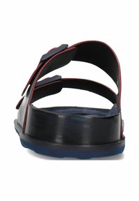 Zwarte leren sandaal met twee verstelbare banden, rode accenten en een blauwe rubberen zool. Schuine kijk vanaf de achterkant, die het open ontwerp benadrukt.