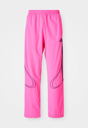Roze sportbroek met een elastische tailleband, zijzakken en contrasterende zwarte gebogen patronen met een Adidas-logo.