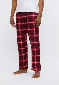 Παντελόνια πιτζάμας με καρό σε κόκκινο, μαύρο και άσπρο, φτιαγμένα από μαλακό ύφασμα. Χαλαρή εφαρμογή με ελαστική μέση και ίσια πόδια.