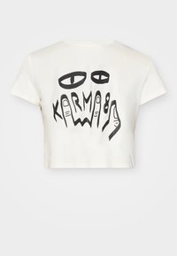 Zugeschnittenes weißes T-Shirt aus Baumwolle mit schwarzem Grafikdesign von Händen und Augen, auf dem das Wort "KARMA" deutlich sichtbar ist.