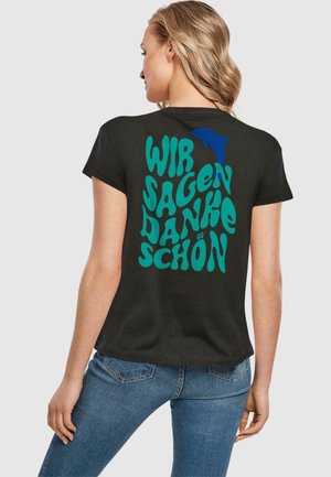 Schwarzes Baumwoll-T-Shirt mit buntem, stilisiertem Text "WIR SAGEN DANKE SCHÖN" in Türkis, begleitet von einer Delfin-Grafik. Kurze Ärmel.
