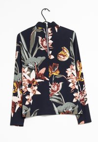 Camicia a maniche lunghe con colletto alto, caratterizzata da un motivo floreale in tonalità di rosa, giallo e verde su sfondo blu navy. Chiusura con zip sul retro.