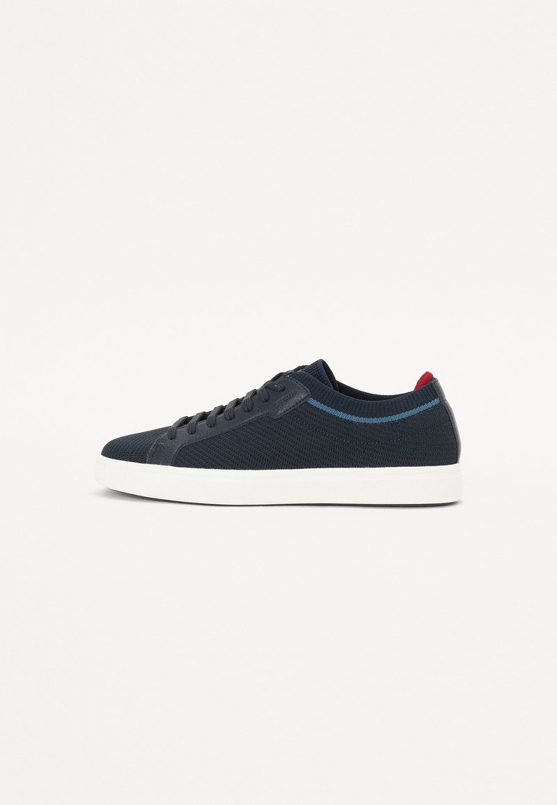 Sneaker in maglia blu navy con suola bianca, design con lacci e accenti a contrasto in azzurro chiaro e rosso sul tallone e sul lato.