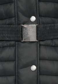 Czarna, pikowana kurtka z metalową klamrą i elastycznym pasem, z zatrzaskami i gładkim, teksturowanym wykończeniem.