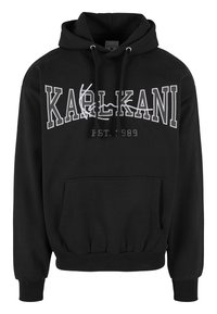 Svart hoodie med kenguruficka, med vit "KARLKANI" text och detalj "EST. 1989". Snörning i huvan och ribbade muddslut. Mjuk tyg.