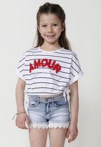Top corto de rayas blancas con texto esponjoso rojo "AMOUR" y detalle "Forever Girl"; combinado con pantalones cortos de mezclilla azul claro con bordes de encaje.