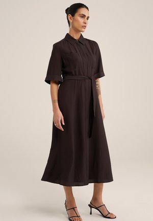 Abito button-up marrone scuro con maniche corte arrotolate, una cintura con nodo in vita e una forma fluida a A realizzato in tessuto leggero.