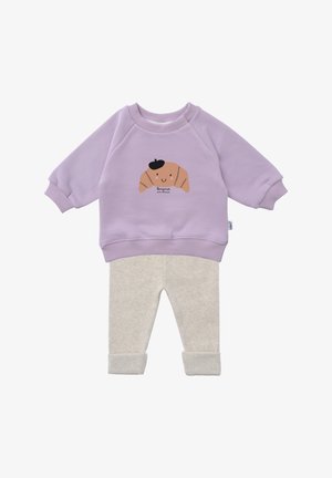Lilac sweatshirt with a croissant graphic and beige pajama pants. The outfit features ribbed cuffs and soft, textured fabric for comfort.