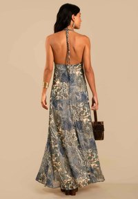 Vestido maxi de tela estampada con colores azul, verde y crema. Diseño de cuello halter con la espalda descubierta y falda fluida.