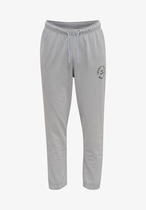 Pantalon de jogging gris clair avec une taille élastique et un cordon de serrage. Présente un petit logo noir imprimé sur la cuisse gauche. Texture de tissu douce.