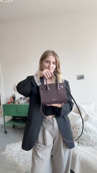 Pieni tummanruskea nahkalaukku, jossa on kuvioitu pinta, kaksi yläkahvaa ja pitkä olkahihna. Hopeanväriset metalliosat.