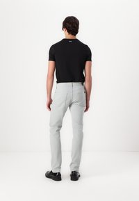 Jeans grii cu croială slim, din material de bumbac, și buzunare la spate. Asortați cu un tricou negru cu mânecă scurtă, cu logo vizibil la gât.