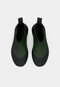 Zielone buty wsuwane z gładką cholewką, czarną gumową podeszwą i teksturowanymi akcentami. Posiadają pętelkę do łatwego zakładania.