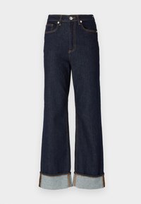 Mangas largas em denim escuro com bainha crua, costura laranja em contraste e dois bolsos frontais; as bainhas dobradas revelam denim mais claro por baixo.