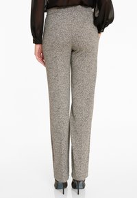 Hoge taille, op maat gemaakte grijs en zwart gestructureerde broeken met een rechte pijp en een zijsplit aan de zoom, gecombineerd met hakken.