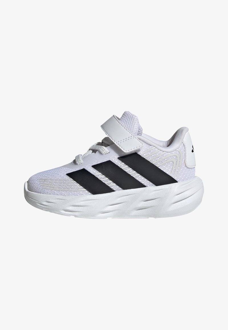 Baskets de sport blanches à rayures noires, semelle épaisse et rembourrée, dessus en mesh, lacets et une bride Velcro sur fond blanc.