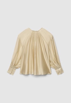 Blouse crème clair avec manches longues bouffantes et dos froncé. Texture lisse et satinée, poignets avec boutons. Col rond.