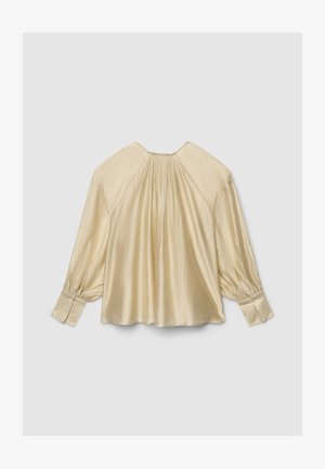 Blusa color crema chiaro con maniche lunghe a sbuffo e schiena arricciata. Tessuto liscio, simile al raso, con polsini abbottonati. Design con scollo rotondo.