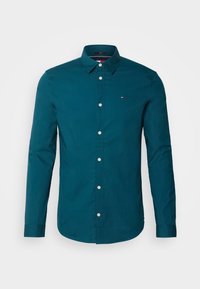 Chemise à manches longues vert turquoise en coton avec un col boutonné, ornée de boutons blancs et d'un petit logo sur la poitrine gauche.