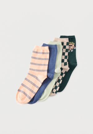 Cinq chaussettes basses colorées alignées côte à côte, comprenant des rayées, unies, à carreaux et une chaussette vert foncé avec un visage de dessin animé.