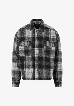 Čierno-biely kockovaný flanelový košeľa s golierom, dvoma prednými vreckami a hnedými gombíkmi. Mäkka textúra a uvoľnený strih.