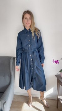 Denimist nööbitev kleit, millel on pikad varrukad, kinni tiessega vöökoht ja täiskleit. Kreemivarvusega nööbid ja tume sinine kangas.