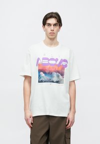 Fehér pamut póló, színes felhő grafikával, előlapján lila felirattal: "FLY ABOVE" és "THERE IS NO LIMIT".