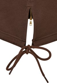 Tissu marron avec une fermeture éclair partiellement ouverte au-dessus d'un nœud de cordon noué, montrant des coutures et une texture tricotée.