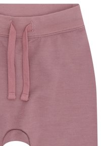Nahaufnahme des Taillenbunds von lila Sweatpants mit einem Kordelzug und sichtbaren Steppnähten.