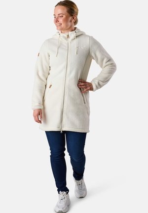 White fleece hooded coat with zip closure, side pockets, and drawstring hood, paired with blue jeans and white sneakers.