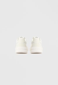 Baskets blanches avec une tige synthétique lisse, un bout arrondi et une semelle blanche rembourrée. Présentent un design minimaliste avec des accents de couture subtils.