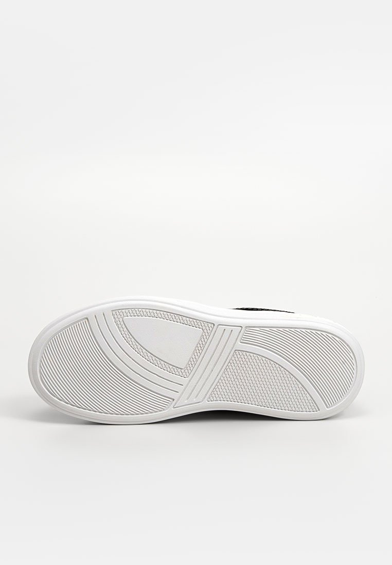 Suola di sneaker nera con una base in gomma bianca testurizzata. Presenta un motivo a onda e profonde scanalature per la trazione e la presa.