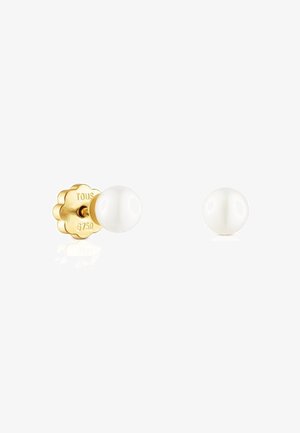 Pendientes de botón de tono dorado con perlas blancas. La parte trasera tiene un diseño escallopado, estampado con "TOUS" y "6750", lo que indica calidad.