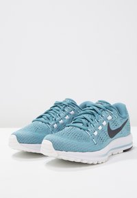 Světlomodré sportovní boty s texturovaným síťovaným svrškem, bílými detaily a černým logem Nike swoosh. Zaoblená bílá podrážka s grip vzorem.