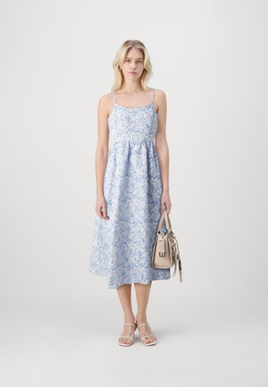 Light blue floral dress with thin straps, flowing A-line silhouette, and a gathered waist. Paired with a beige handbag and sandals.