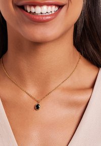 Collier en chaîne en or avec un pendentif en pierre précieuse noire ronde, avec une finition polie et un design de maillon délicat.