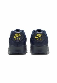 Nike Air tossud tumesinise ülemise osaga, tekstuurse kanna ja kollaste logode aktsentidega. Omab pehmendatud tagumist osa ja vastupidavat kummist tallat.