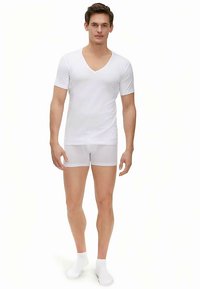 White V-neck t-shirt with short sleeves, paired with white fitted shorts. Smooth fabric texture with a minimalist design.