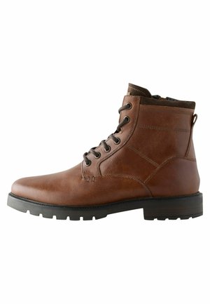 Brown leather ankle boot with a rounded toe, black rubber sole, and metal eyelets. Features stitching details and a pull tab at the back.