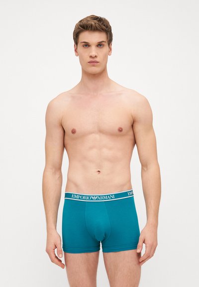 Tirkizne muške bokserice s elastičnom trakom na kojoj je logo "EMPORIO ARMANI". Glatka tkanina, kroj koji se savršeno prilagođava s oblikovanim džepom.