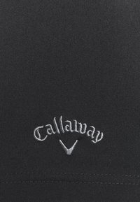 Juodas audinys su tekstūru pasižymi baltu siuvinėjimu "Callaway" logotipu, po kuriuo yra golfo tees simbolis.
