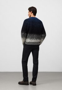 Sweter dzianinowy o gradientowym wzorze, przechodzącym od ciemnoniebieskiego do szarego. W połączeniu z ciemnymi spodniami i brązowymi botkami na kostkę. Gładka faktura.