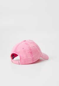 Rosa baseballkeps i denimliknande tyg, med en böjd skärm, sömnadsdetaljer och en justerbar bakrem.
