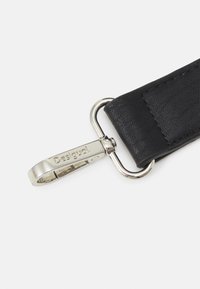 Cinturino in pelle nera con clip in metallo argento. Presenta una superficie texturizzata e un logo inciso. Adatto per borse o accessori.