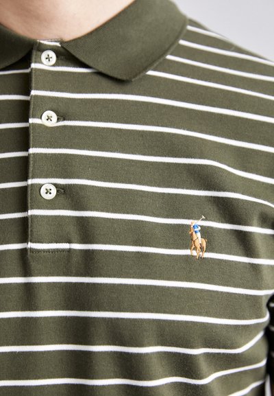 Zaļa un balta svītrainā polo krekls ar mīkstu tekstūru. Tam ir apkakle, trīs pogas un izšūts logo ar zirgu un jātnieku.
