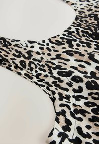 Canotta con motivo a stampa leopardata beige e nera, realizzata in tessuto leggero, con scollatura rotonda e cuciture pulite.