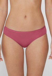 Bikini v tlumené růžové barvě, vyrobené z hladké látky, s nízkým pasem a minimalistickým designem bez viditelných vzorů nebo kovových prvků.