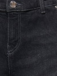 Juodas džinsinis audinys iš arti, matomas priekinis kišenė, diržo kilpa ir metalinis mygtukas su išgraviruotu tekstu.